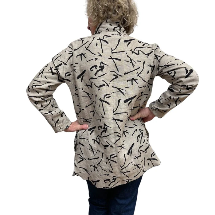 Person wearing a beige shirt with black abstract patterns on a white background