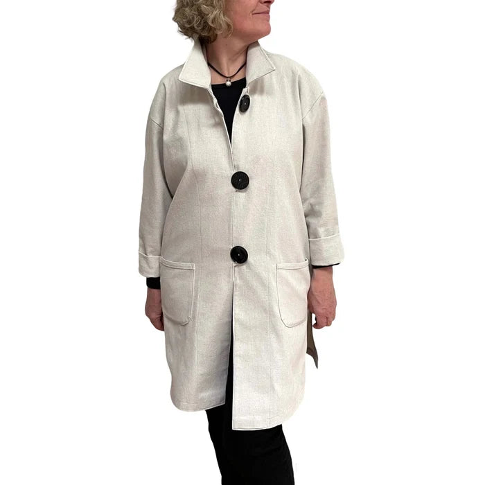 Woman wearing a beige coat with black buttons on a white background