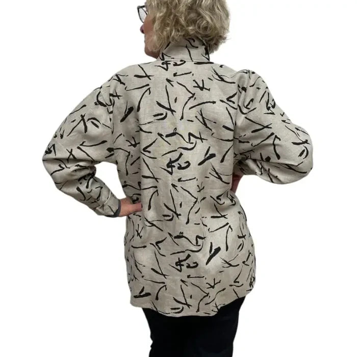 Person wearing a beige shirt with black abstract patterns on a white background