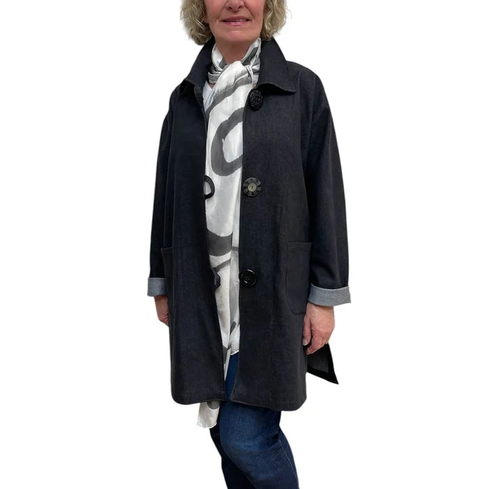 Woman wearing a dark coat with a patterned scarf on a white background
