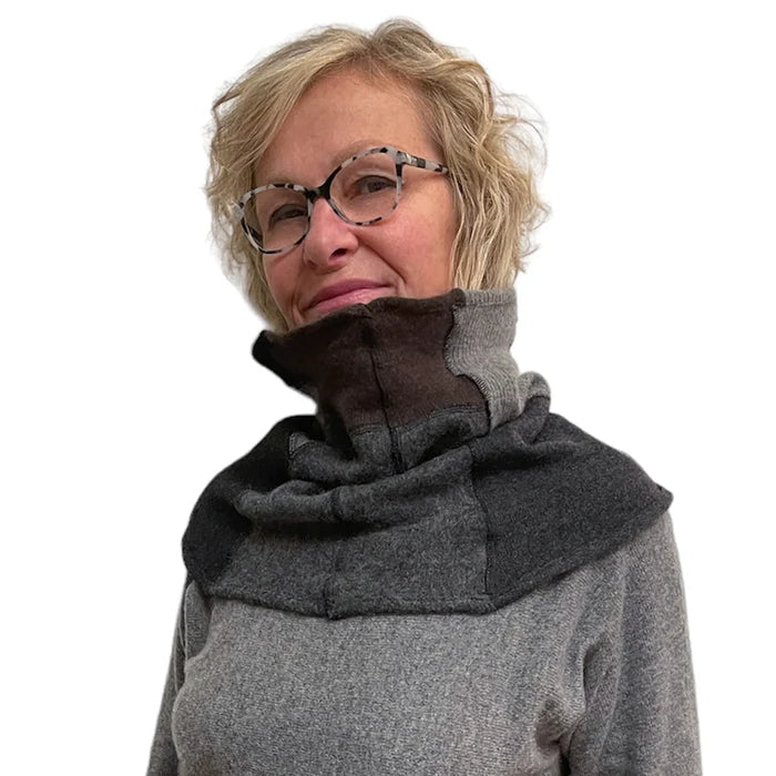 Person wearing a gray and black cowl neck garment on a white background