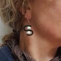 Close-up of a person wearing a unique earring with two pearls.