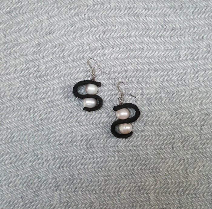 Pair of earrings with pearls on a gray textured background