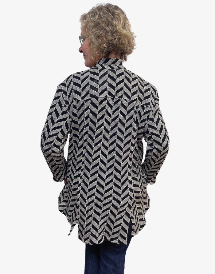 Person wearing a black and white patterned jacket on a white background