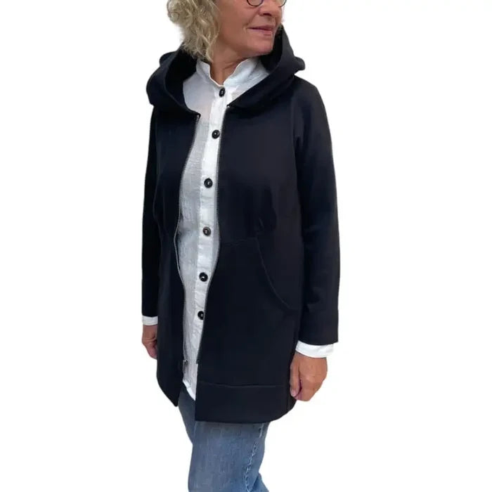 Person wearing a black coat with a white shirt and blue jeans on a white background
