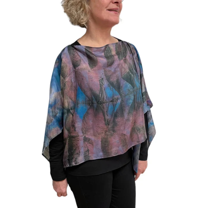 Woman wearing a colorful poncho with abstract patterns on a white background