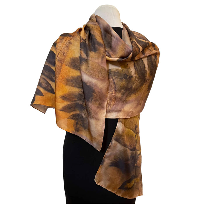 Brown and orange patterned scarf on a mannequin against a white background