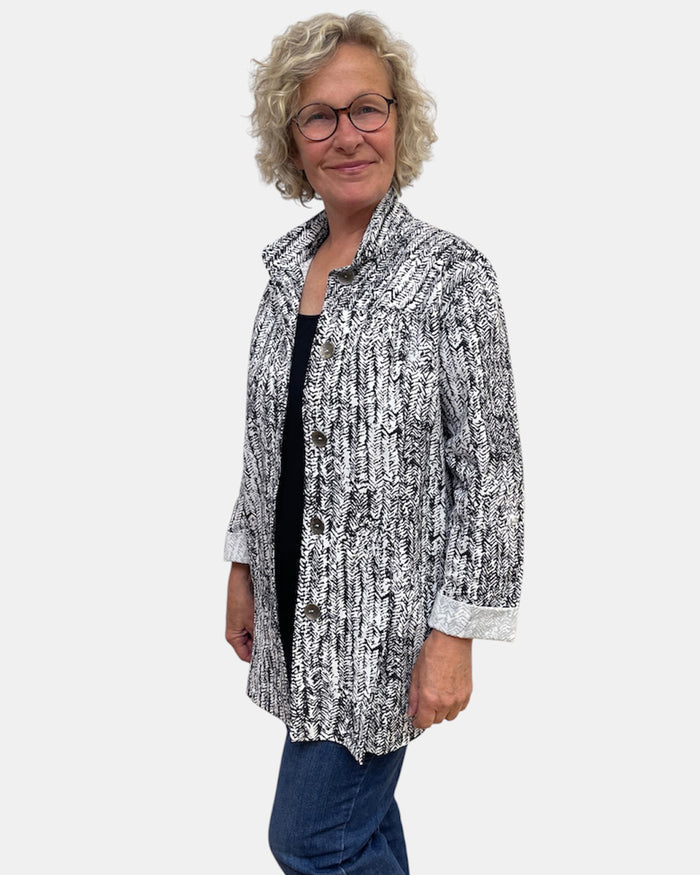 Woman wearing a black and white patterned jacket on a white background