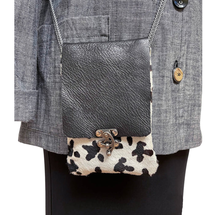 Gray textured handbag with cow print flap over a gray coat