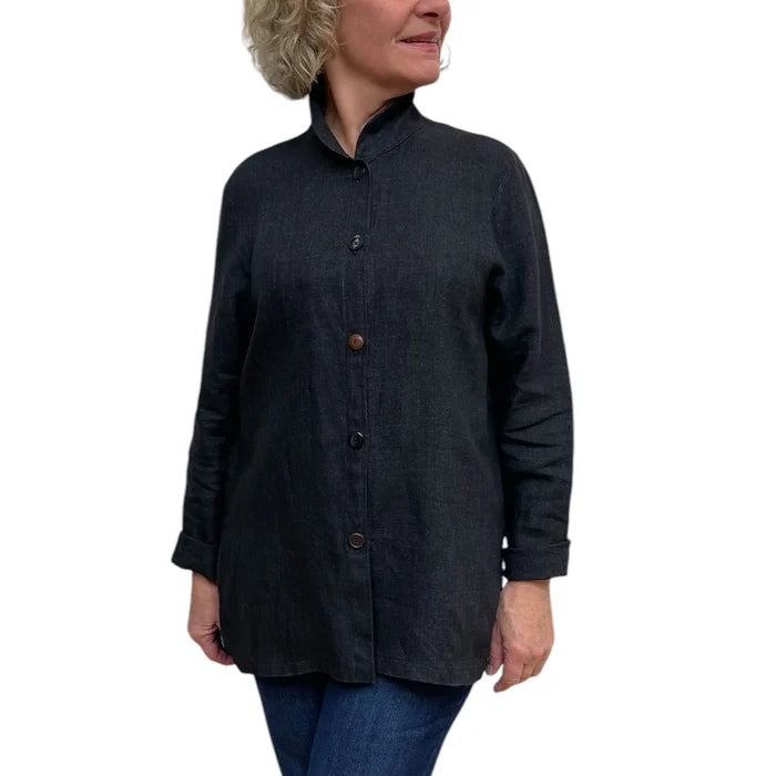 Person wearing a dark denim shirt with button details on a white background