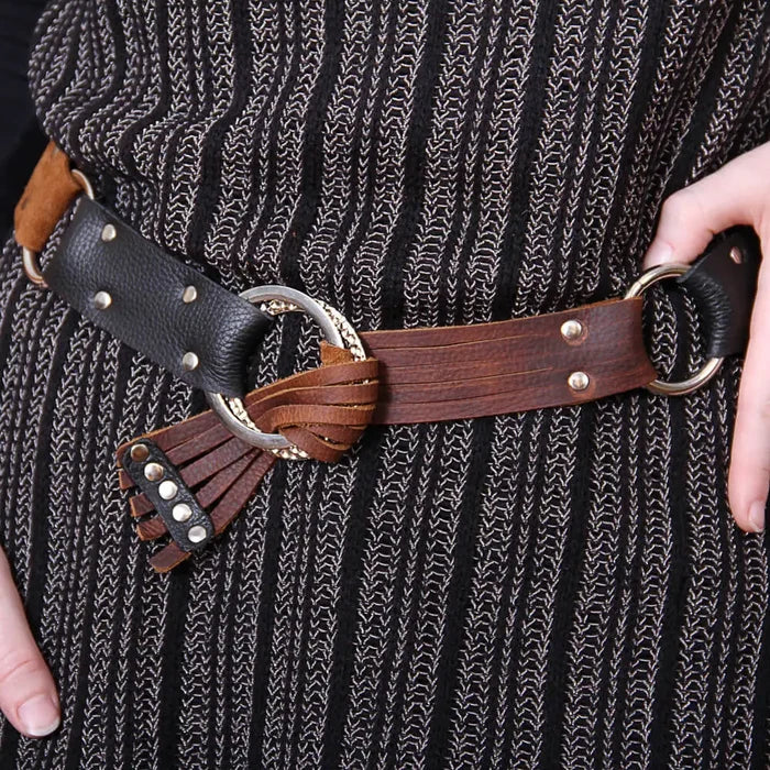 Close-up of a person wearing a brown leather belt with decorative elements.