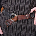 Close-up of a person wearing a brown leather belt with decorative elements.