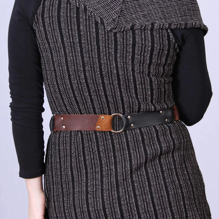 Person wearing a black knit dress with a brown belt on a light purple background