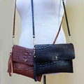 Two leather handbags, one brown and one black, on a mannequin with a beige background.