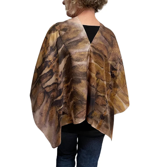 Person wearing a brown and beige patterned poncho on a white background
