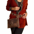 Person wearing a red coat holding a brown leather bag on a white background