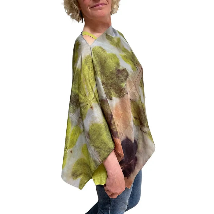 Person wearing a green and brown patterned poncho on a white background
