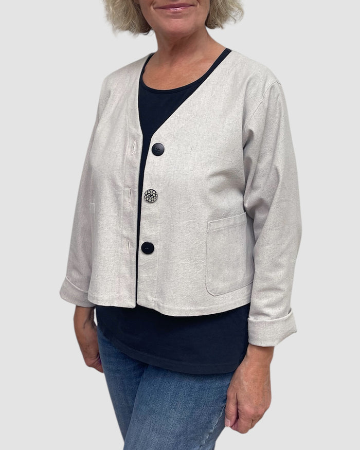 Person wearing a light gray jacket with black buttons on a white background