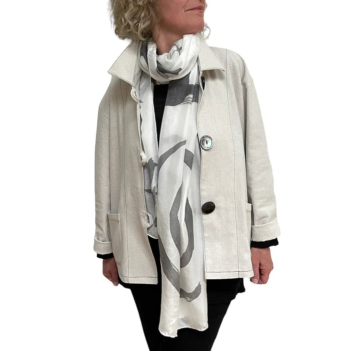 Person wearing a light-colored coat and a patterned scarf on a white background