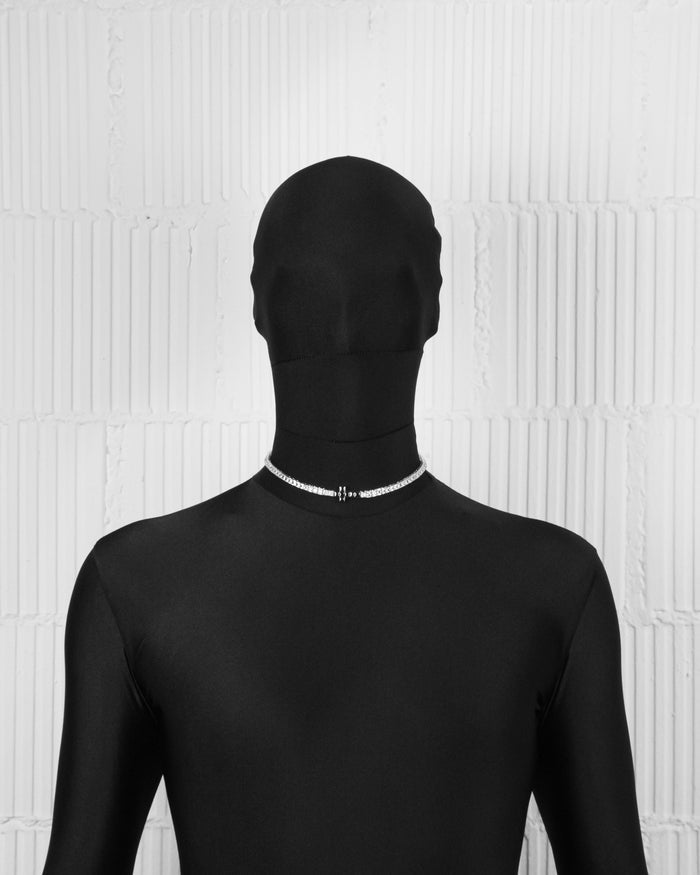 man with black suit wearing 18k white gold and black coated tennis chain necklace with contrasting cross element and hand-set princess-cut stones in white and black