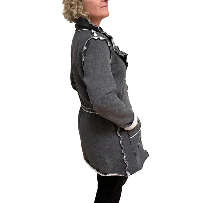 Person wearing a gray coat with decorative trim on a white background