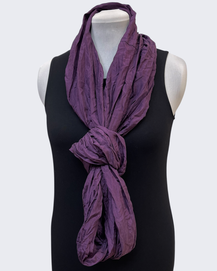 Purple scarf draped over a black sleeveless top on a mannequin against a white background