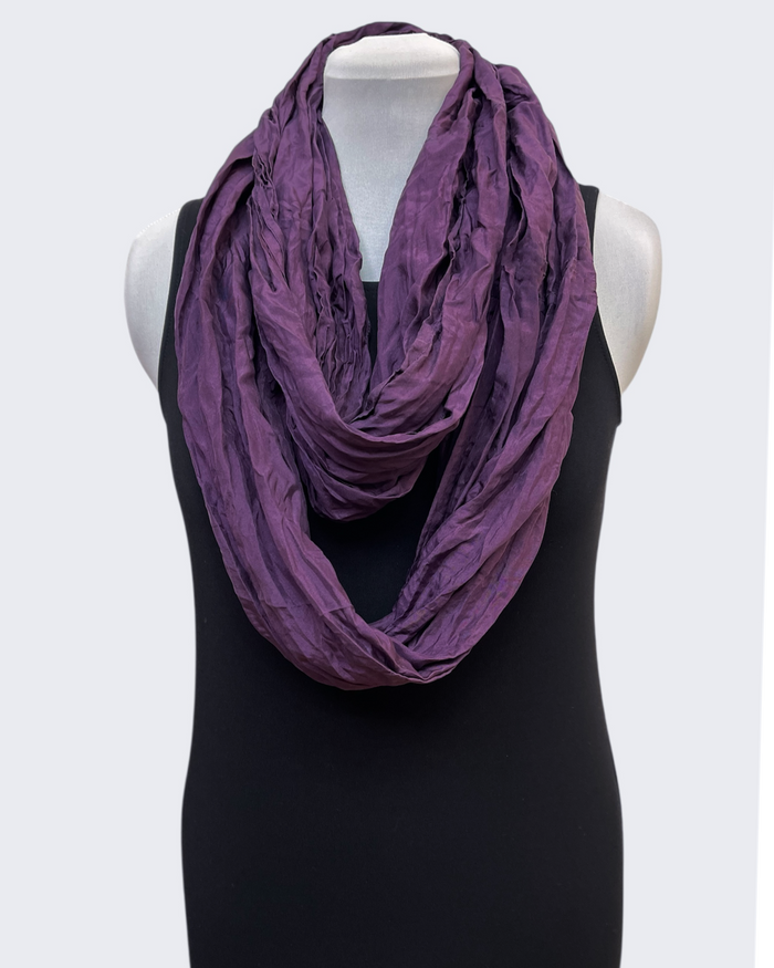 Purple scarf draped around a black dress on a mannequin against a white background