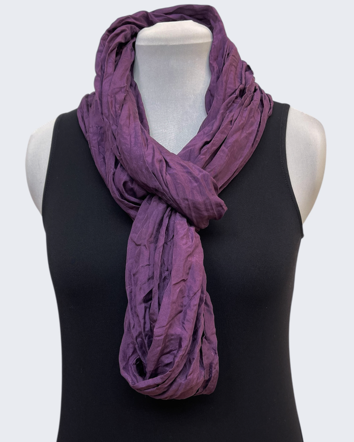 Purple scarf draped over a black top on a mannequin against a white background