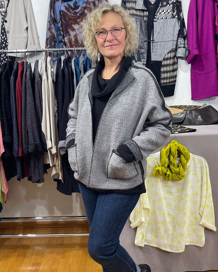 Woman standing in a clothing store with racks of clothes in the background