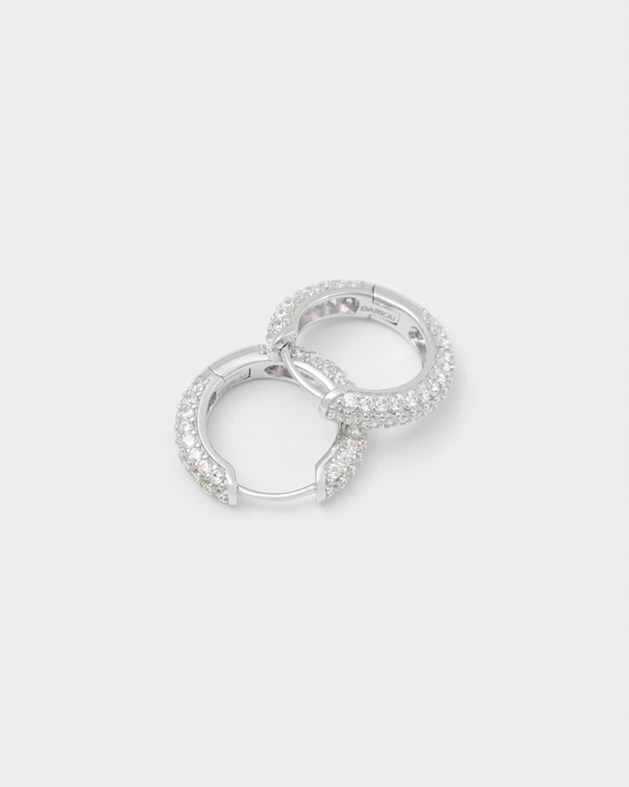 detail of 18k white gold coated hoop earrings with all around hand-set micropavé stones in white and lasered logo on the inside.