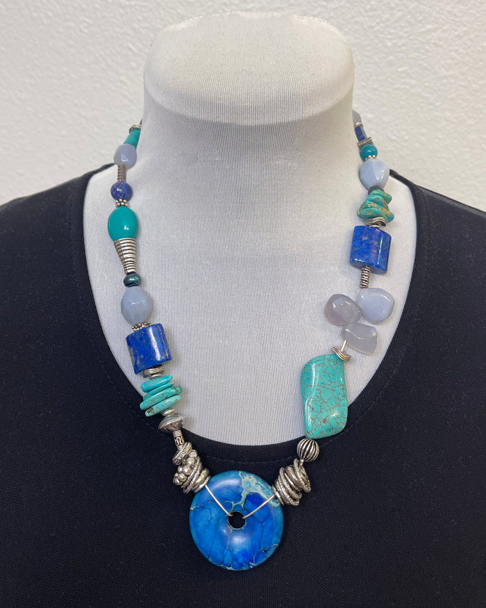 Necklace with blue and turquoise beads on a mannequin against a white background