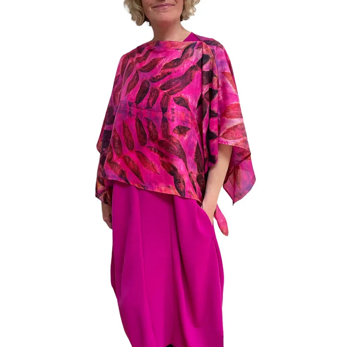 Woman wearing a vibrant pink and red patterned top with a plain background