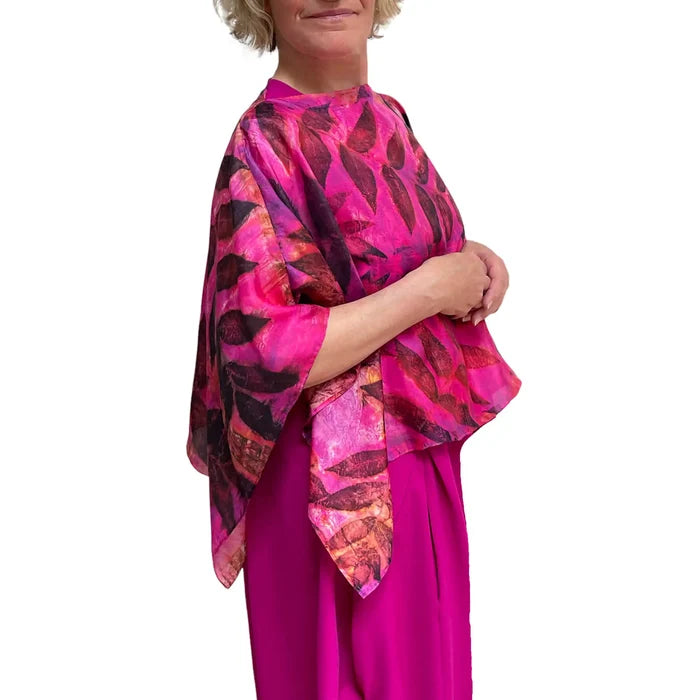 Woman wearing a vibrant pink and purple patterned top with a white background