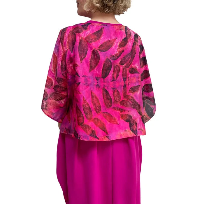 Person wearing a vibrant pink and red patterned top with a plain background
