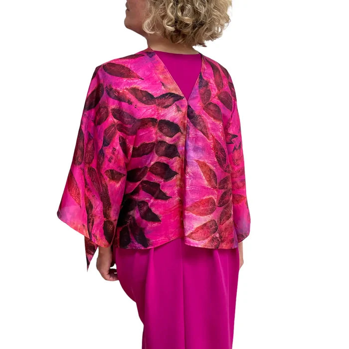 Woman wearing a pink and red patterned jacket over a pink dress on a white background