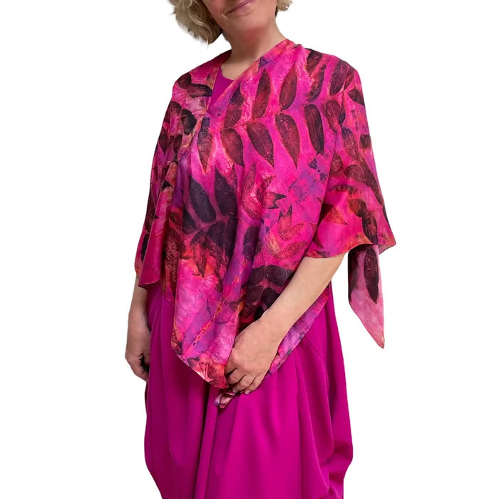 Woman wearing a vibrant pink and red patterned top with a matching skirt on a white background