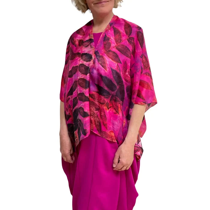 Person wearing a vibrant pink and red patterned top with a plain background