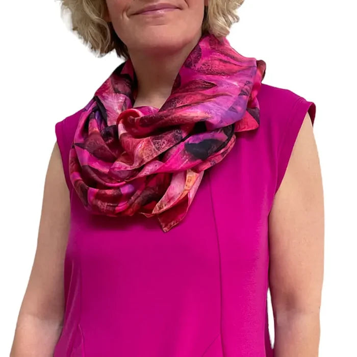 Woman wearing a bright pink sleeveless top and a colorful scarf on a white background
