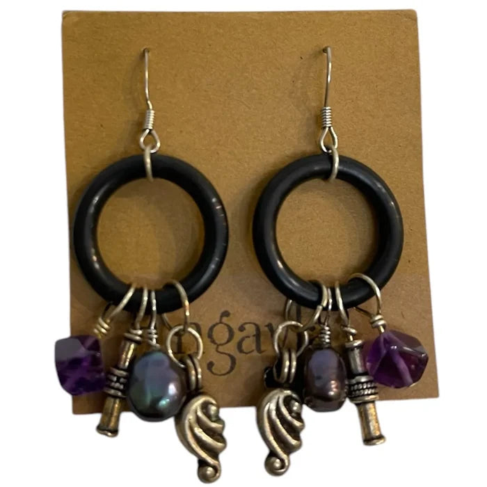 Pair of earrings with black rings, purple beads, and gold charms on a brown card.