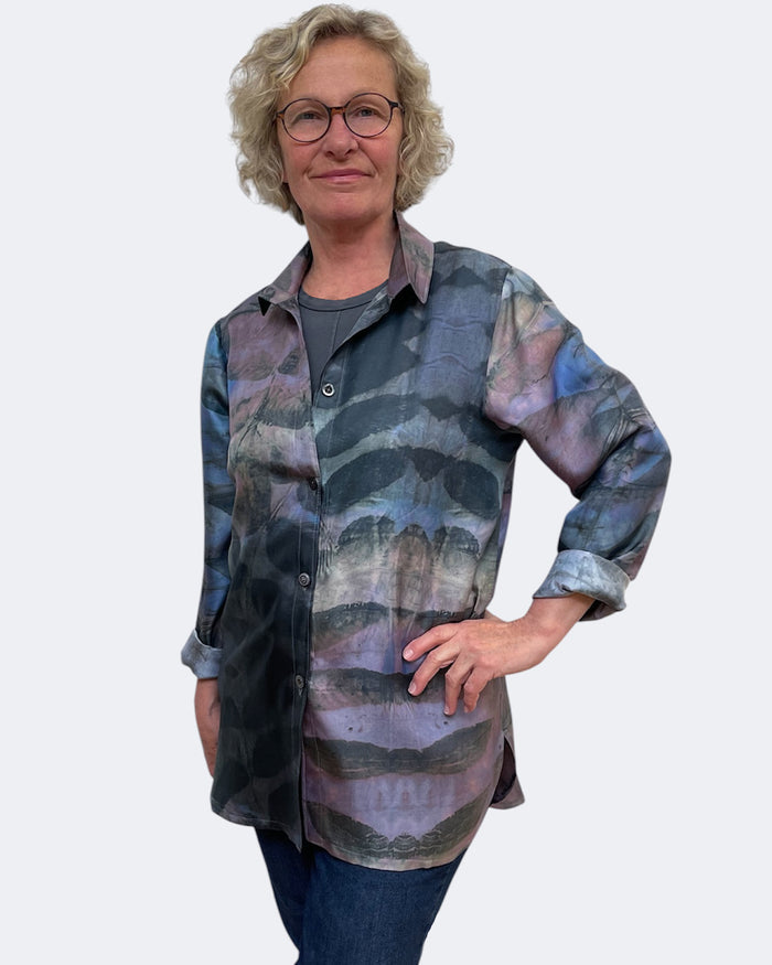 Person wearing a patterned shirt on a plain background