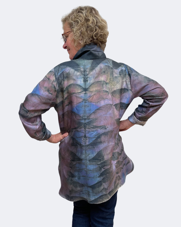 Person wearing a patterned shirt with their back to the camera on a white background