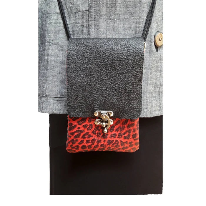Gray crossbody bag with red leopard print accent held by a person wearing a gray jacket.