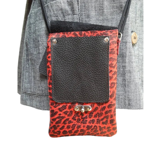 Black phone pouch with red leopard print strap attached to a gray jacket.