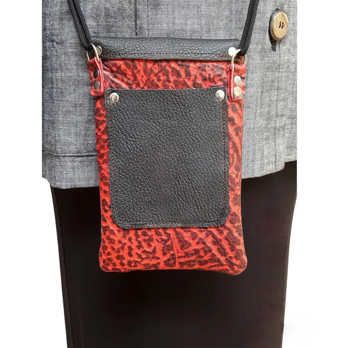 Red leopard print crossbody bag with black leather pocket on a gray background
