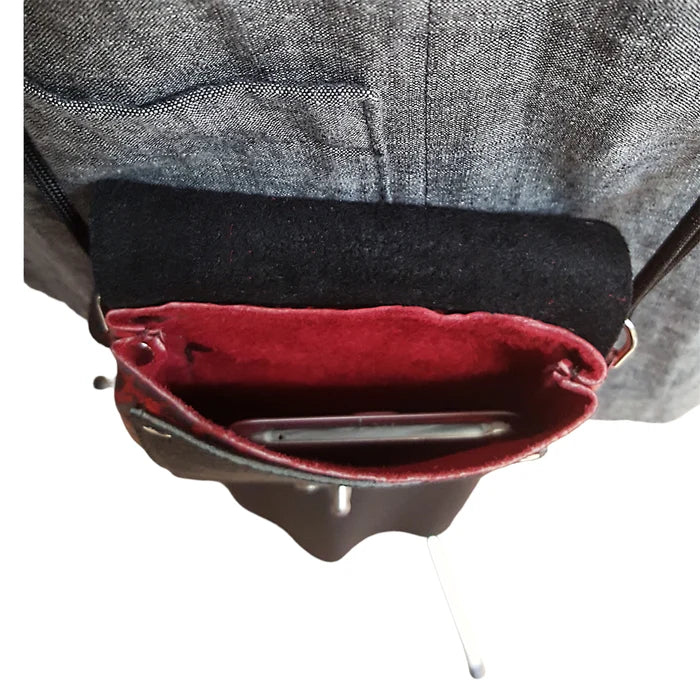 Close-up of a red interior pocket with a metal object, worn by a person in a gray jacket.