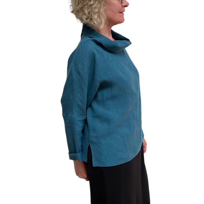Person wearing a blue cowl-necked top on a white background