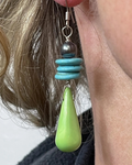 Close-up of earrings with turquoise beads and a green teardrop pendant.