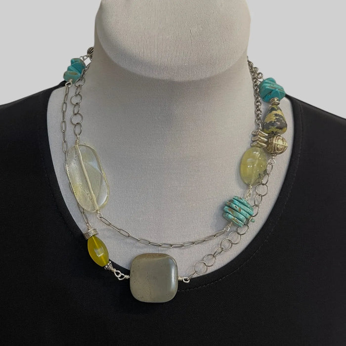 Necklace with colorful beads on a mannequin bust against a plain background