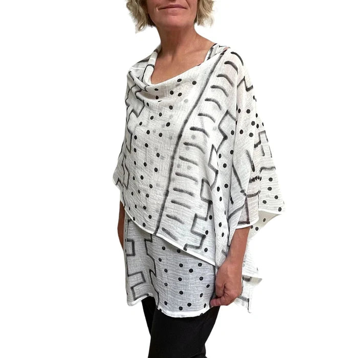 Woman wearing a white poncho with black geometric patterns on a white background
