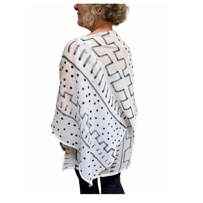 Person wearing a white and black patterned poncho on a white background